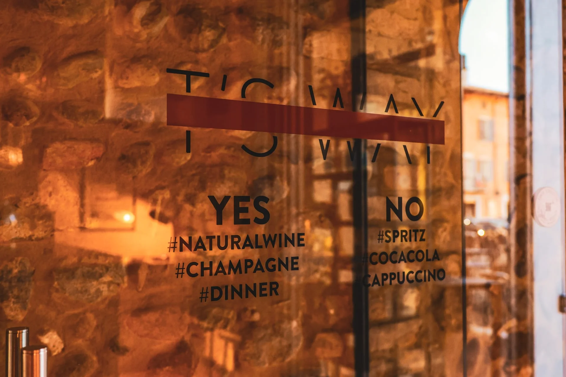 La vetrina di T'S WAY con il logo e le scritte sul vetro, affacciata sulla piazza La vetrina di T'S WAY con il logo e le scritte sul vetro, affacciata sulla piazza