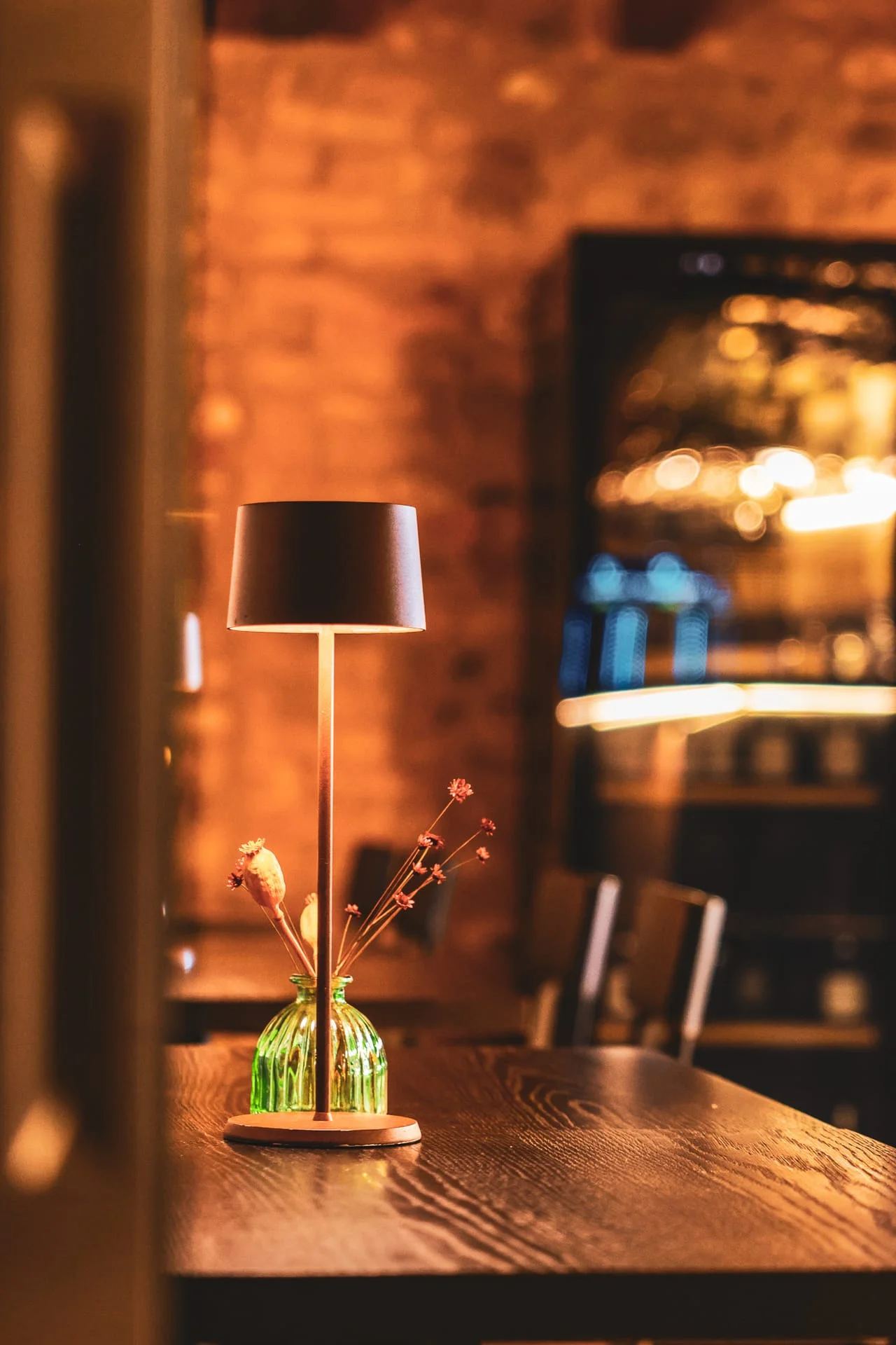 Tavolo con lampada e vasetto di fiori nella luce calda della sera Tavolo con lampada e vasetto di fiori nella luce calda della sera