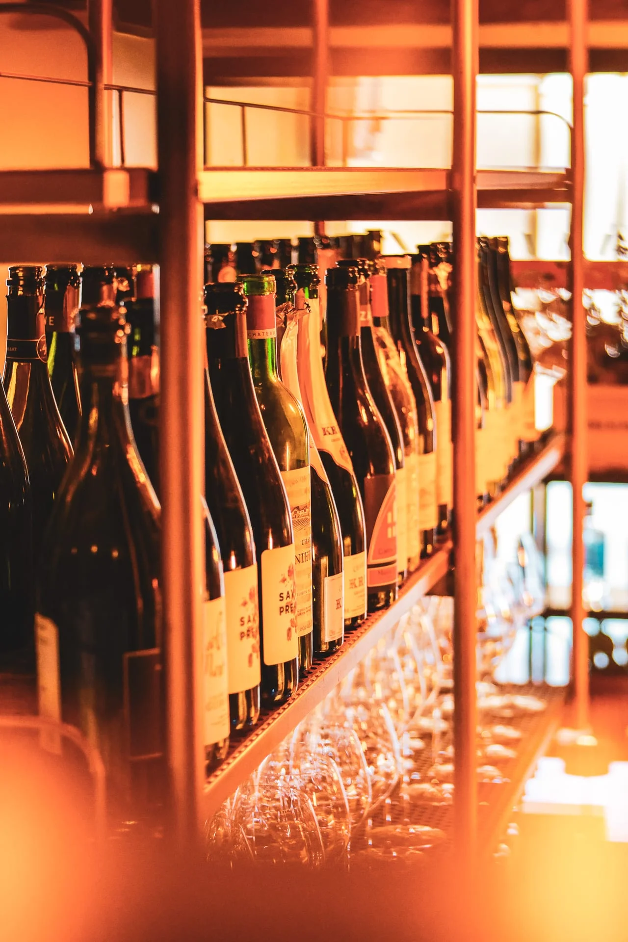 Bottiglie di vino allineate sugli scaffali in ferro sopra il bancone Bottiglie di vino allineate sugli scaffali in ferro sopra il bancone
